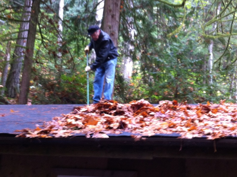     Brian Lindvall sweeping leaves off of lower part of long building
